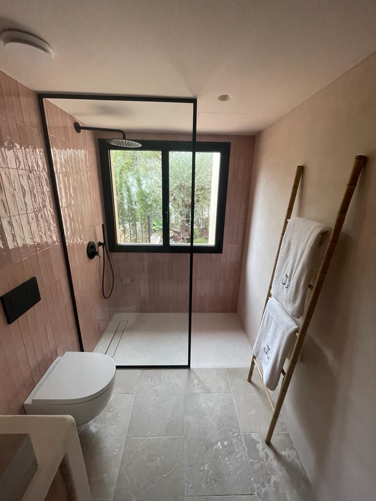 Un baño con inodoro, lavabo, ducha y ventana.