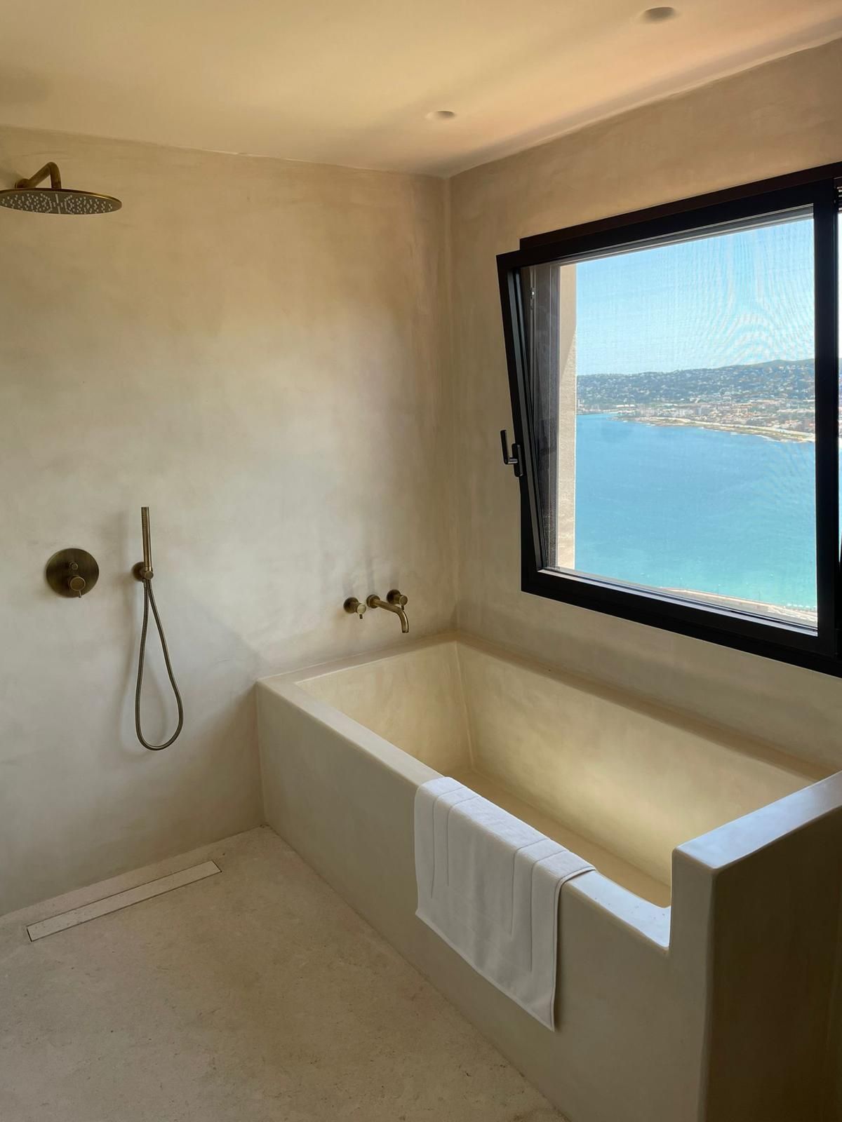 Un baño con bañera y una ventana con vista al mar.