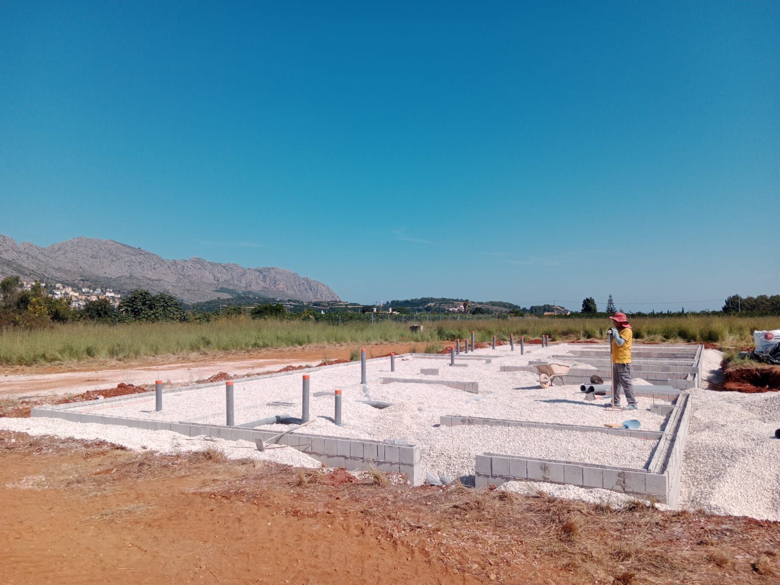Un hombre está parado en medio de un campo de tierra.