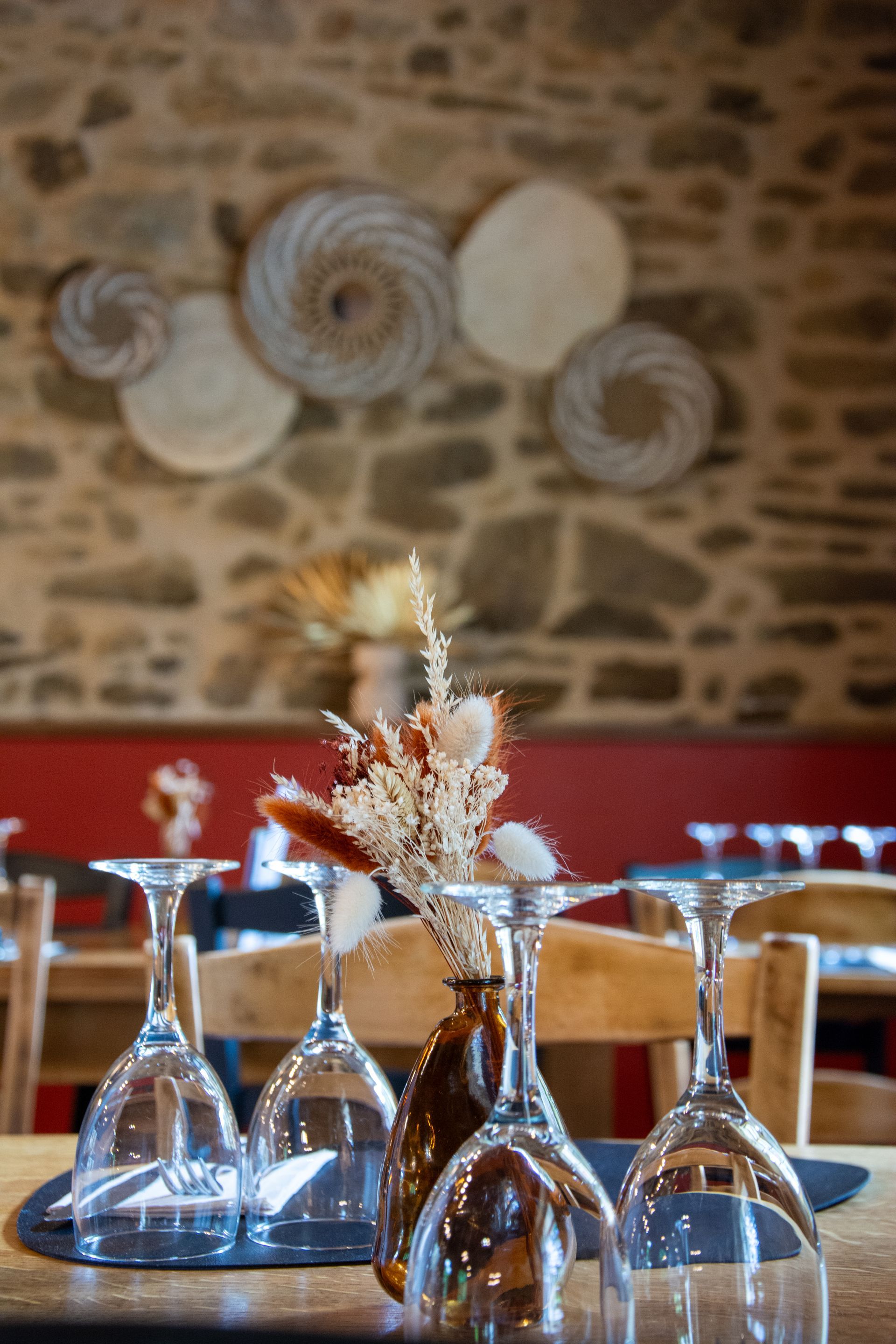 Dressage de table au restaurant avec verres à vin et fleurs séchées ; décoration murale.