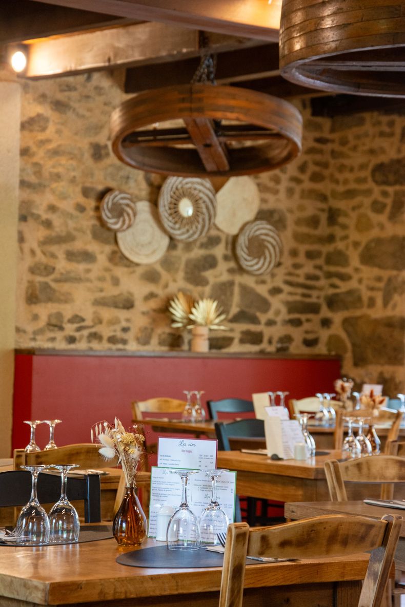 Table de restaurant dressée avec des verres à vin, un vase de fleurs et un menu.
