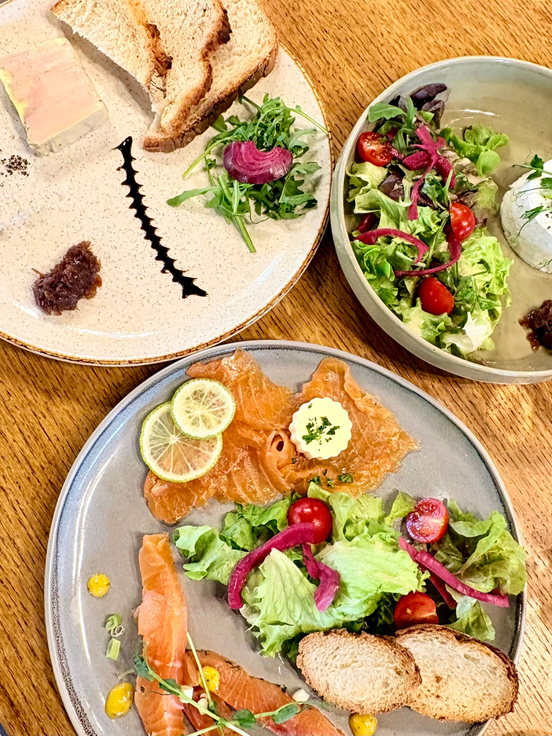 Poisson poêlé avec des tranches de citron, des pommes de terre et un mélange de légumes sur une assiette blanche.