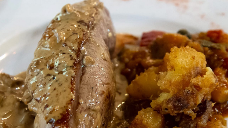 Plat de pâté garni de feuilles, servi avec des cornichons dans de petits plats blancs.