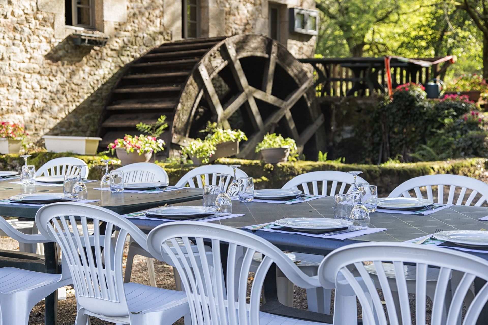 Ensemble de table et chaises blanches pour un repas en plein air, près d'une roue à eau.