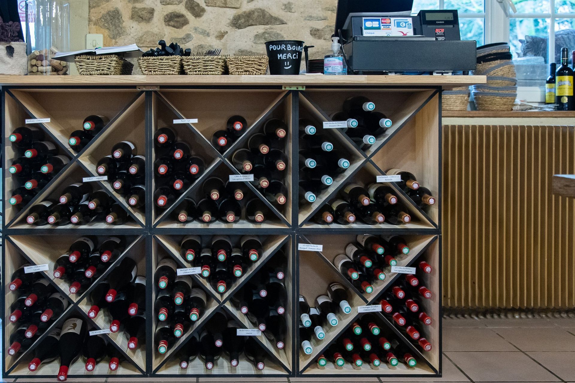 Des bouteilles de vin sont exposées sur un casier en bois derrière le comptoir d'un magasin.