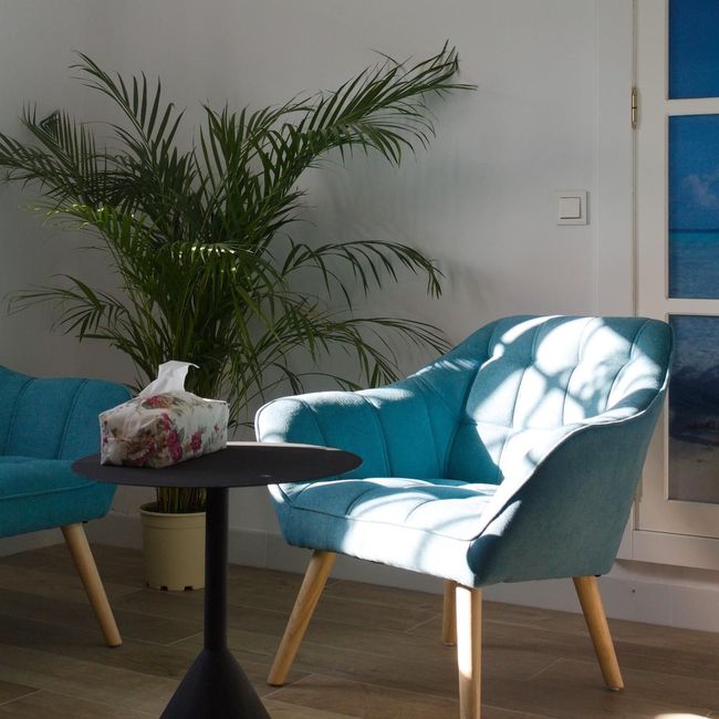 Una silla azul está junto a una mesa con pañuelos encima.