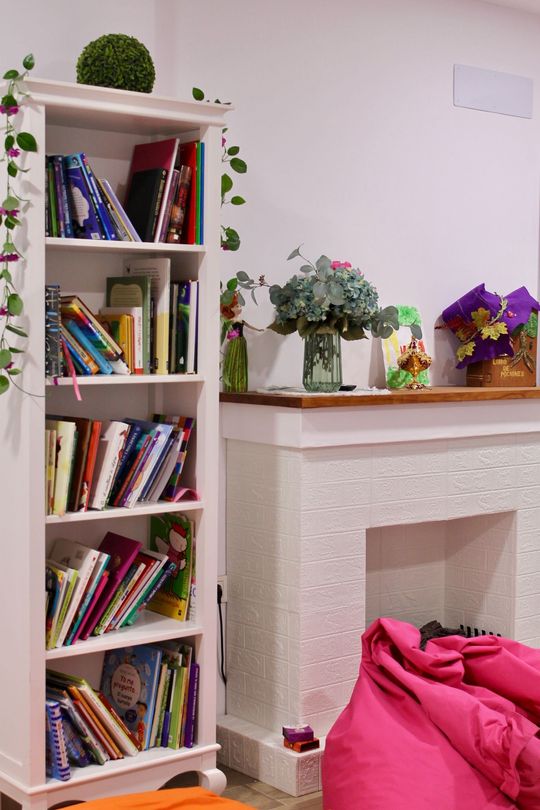 Una estantería llena de libros junto a una chimenea.
