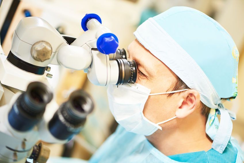 Un cirujano está mirando a través de un microscopio en un quirófano.