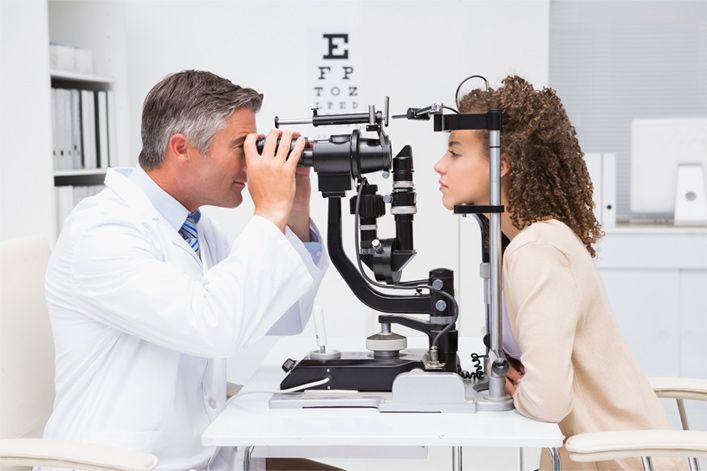 Un médico está examinando el ojo de una mujer con un microscopio.