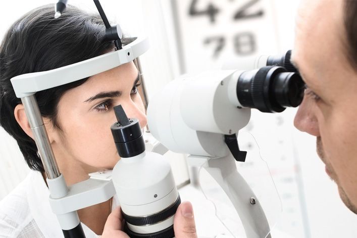 Una mujer se está haciendo examinar los ojos por un oftalmólogo.