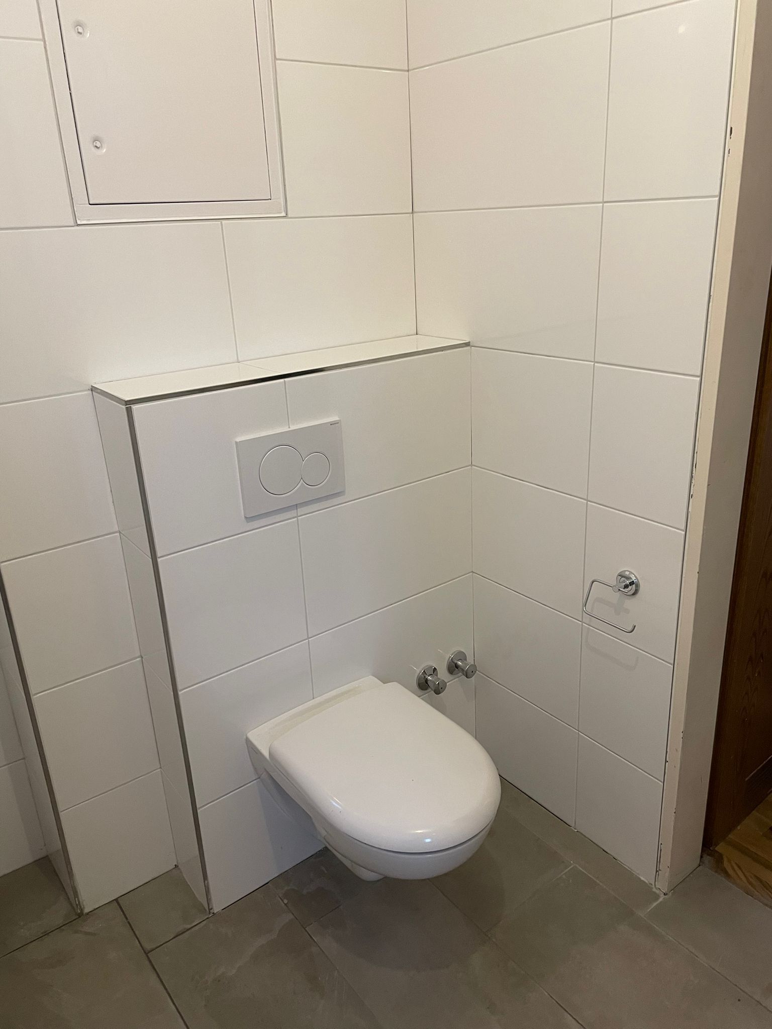 Modernes, weiß gefliestes Badezimmer mit wandmontierter Toilette.