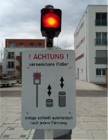 Verkehrsschild mit roter Ampel und Warnung vor versenkbaren Pollern.