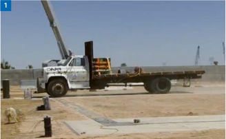 Ein weißer Pritschenwagen in einer Wüstengegend mit einem Kran im Hintergrund.