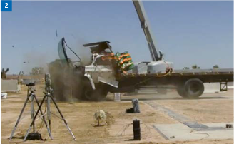 Bei einem Crashtest wird ein Fahrzeug getroffen. Staub und Trümmer fliegen herum, als sich die Ladefläche des Lastwagens hebt.