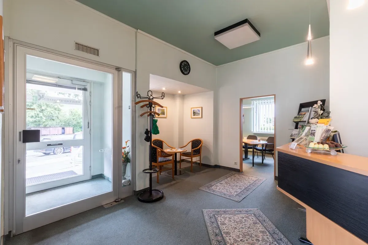 Ein Wartezimmer mit einem Schreibtisch, Stühlen und einer Uhr an der Wand.