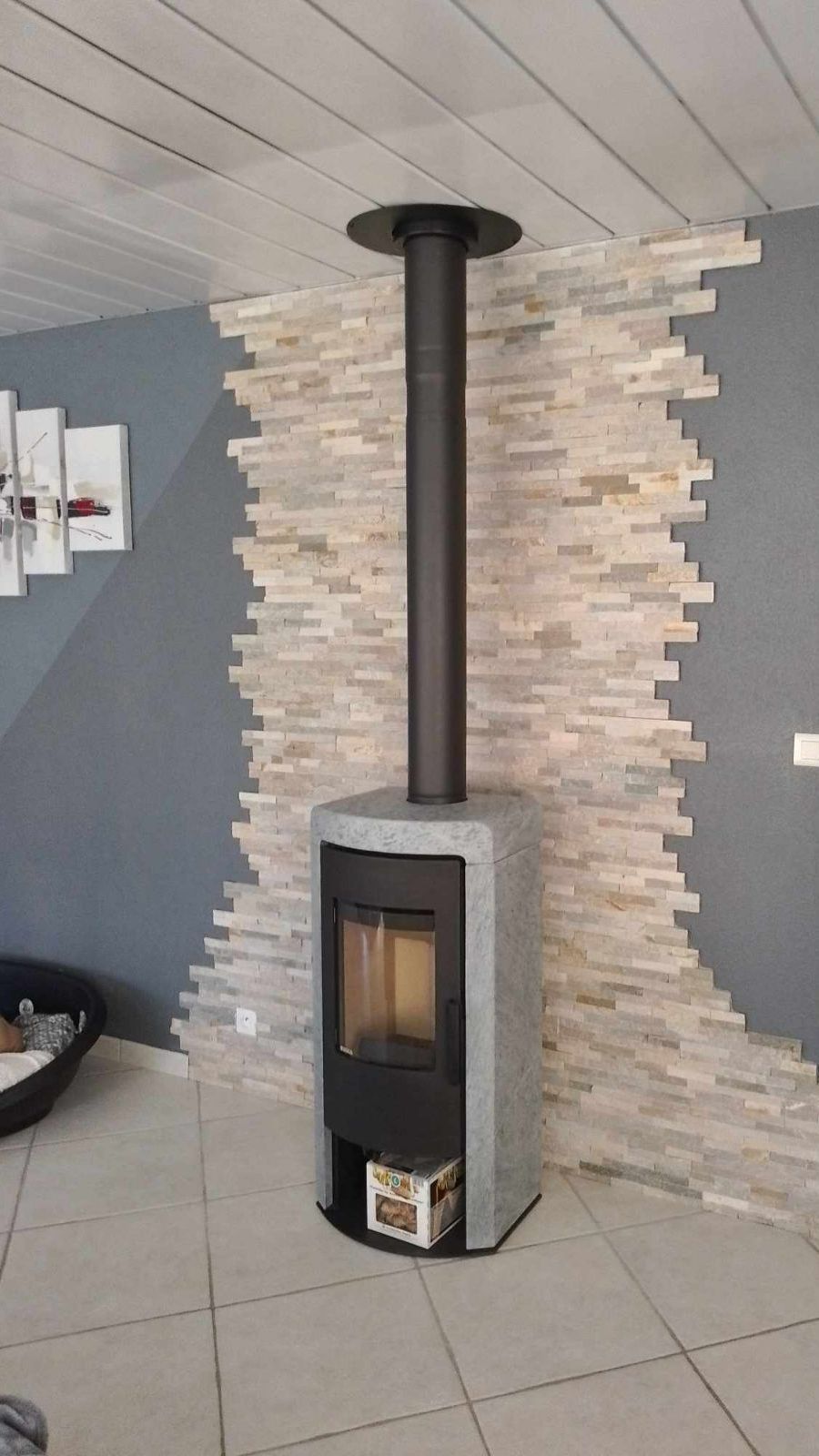 Poêle à bois noir et gris avec protection murale.