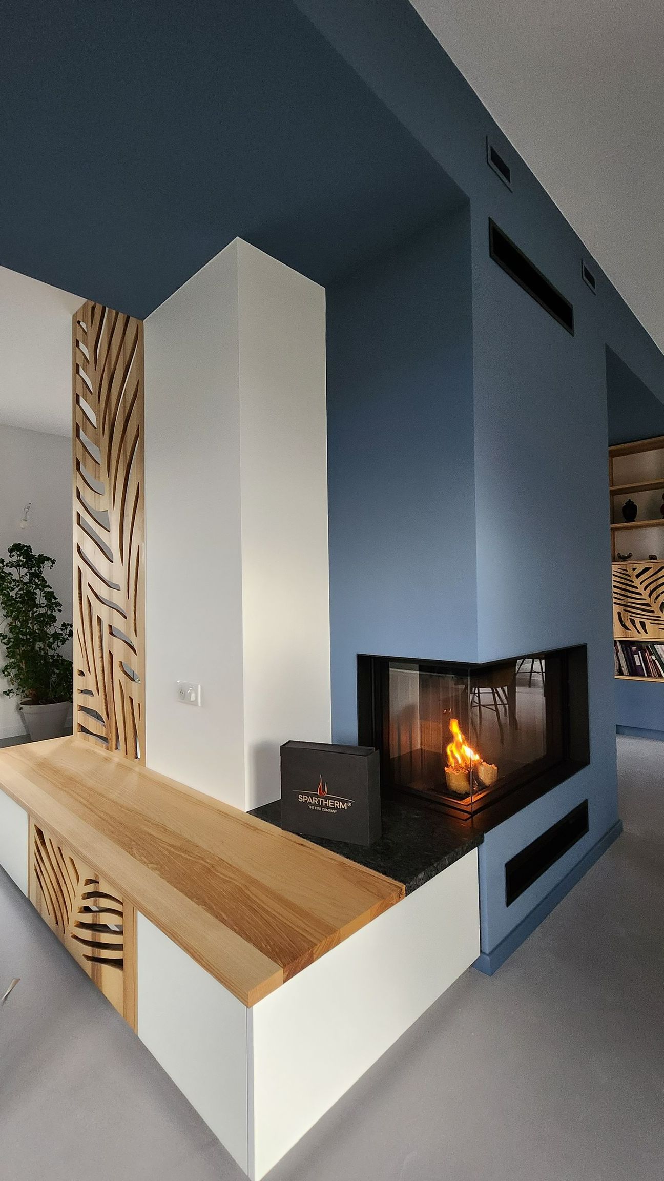 Une cheminée avec insert au centre d'une grande pièce.
