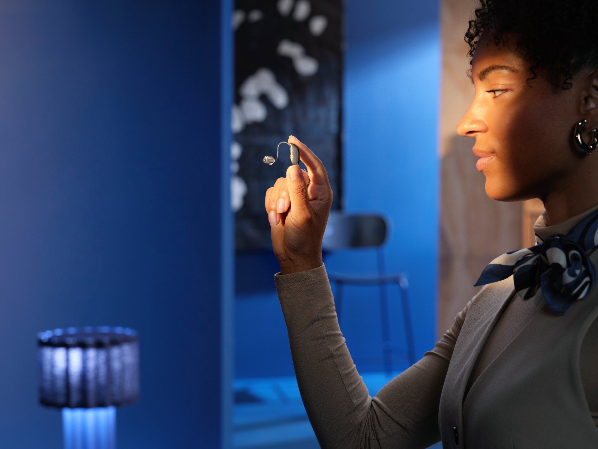 Eine Frau hält ein Hörgerät in der Hand.