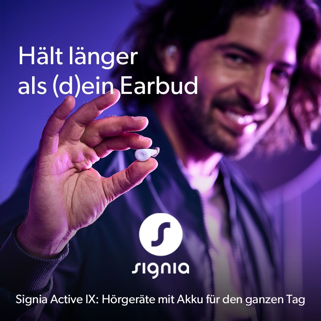 Ein Mann sitzt auf einem blauen Sofa und hält eine Lupe.