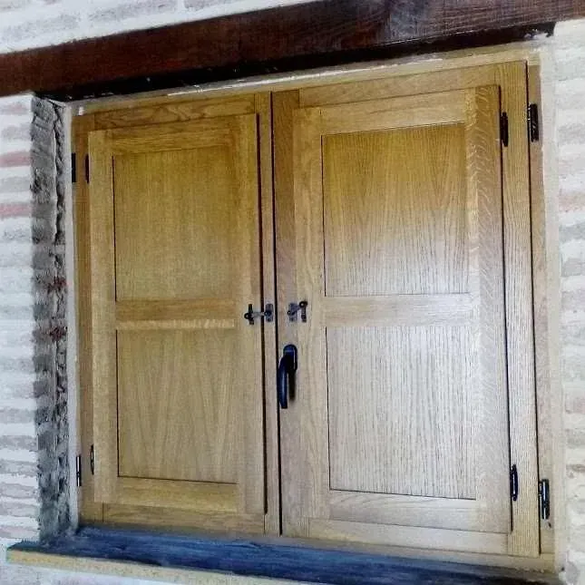 Puerta doble de madera con tiradores de latón, integrada en un hueco de pared de piedra.
