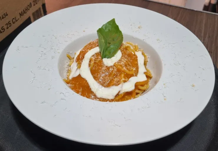 Postre con salsa de naranja, cubierto con crema batida y una hoja de menta, servido en un plato blanco.