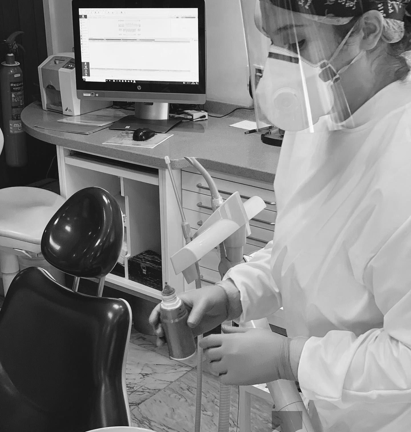 Dentista con equipo de protección, preparando herramientas en un consultorio dental.