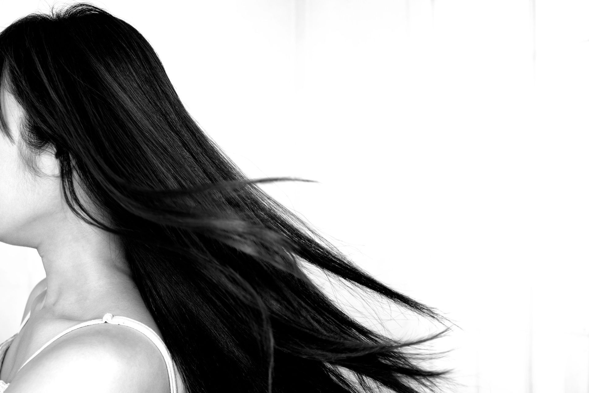 Mujer con cabello largo y oscuro que ondea hacia un lado contra un fondo blanco.