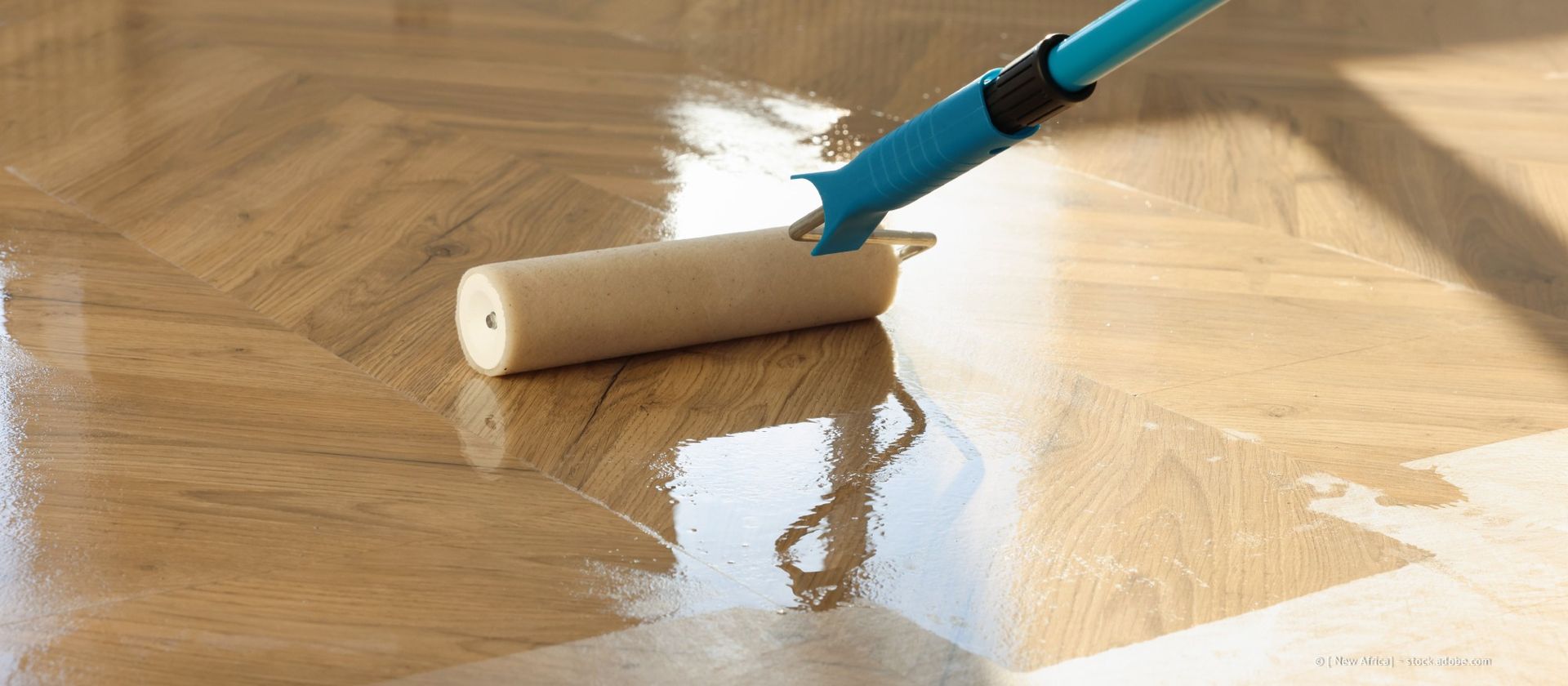 Eine Rolle verleiht einem hellbraunen Hartholzboden ein glänzendes Finish und lässt die Oberfläche erstrahlen.