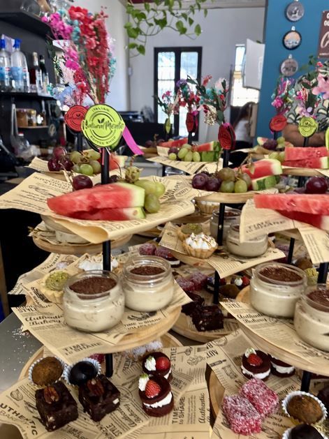 Una exhibición de postres escalonados con rodajas de sandía, uvas, mini pasteles y postres de crema.