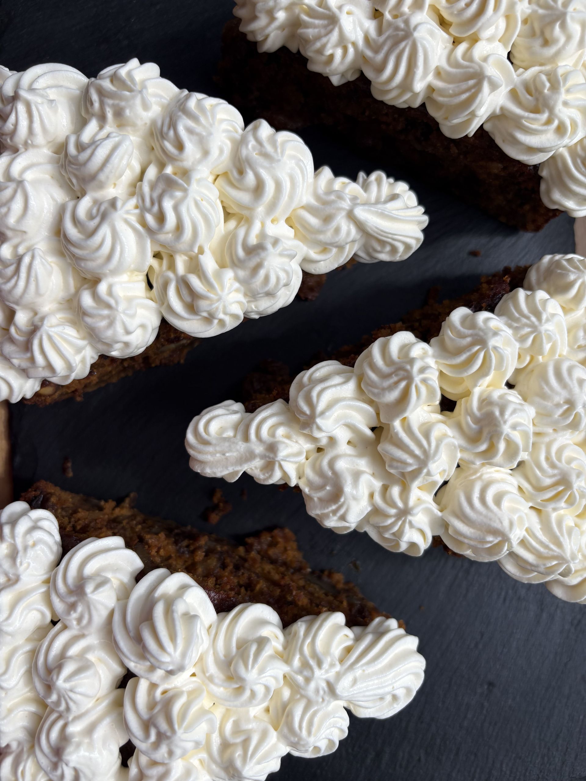 Cuatro rebanadas de pastel con forma de árbol de Navidad, cubiertas con glaseado blanco.