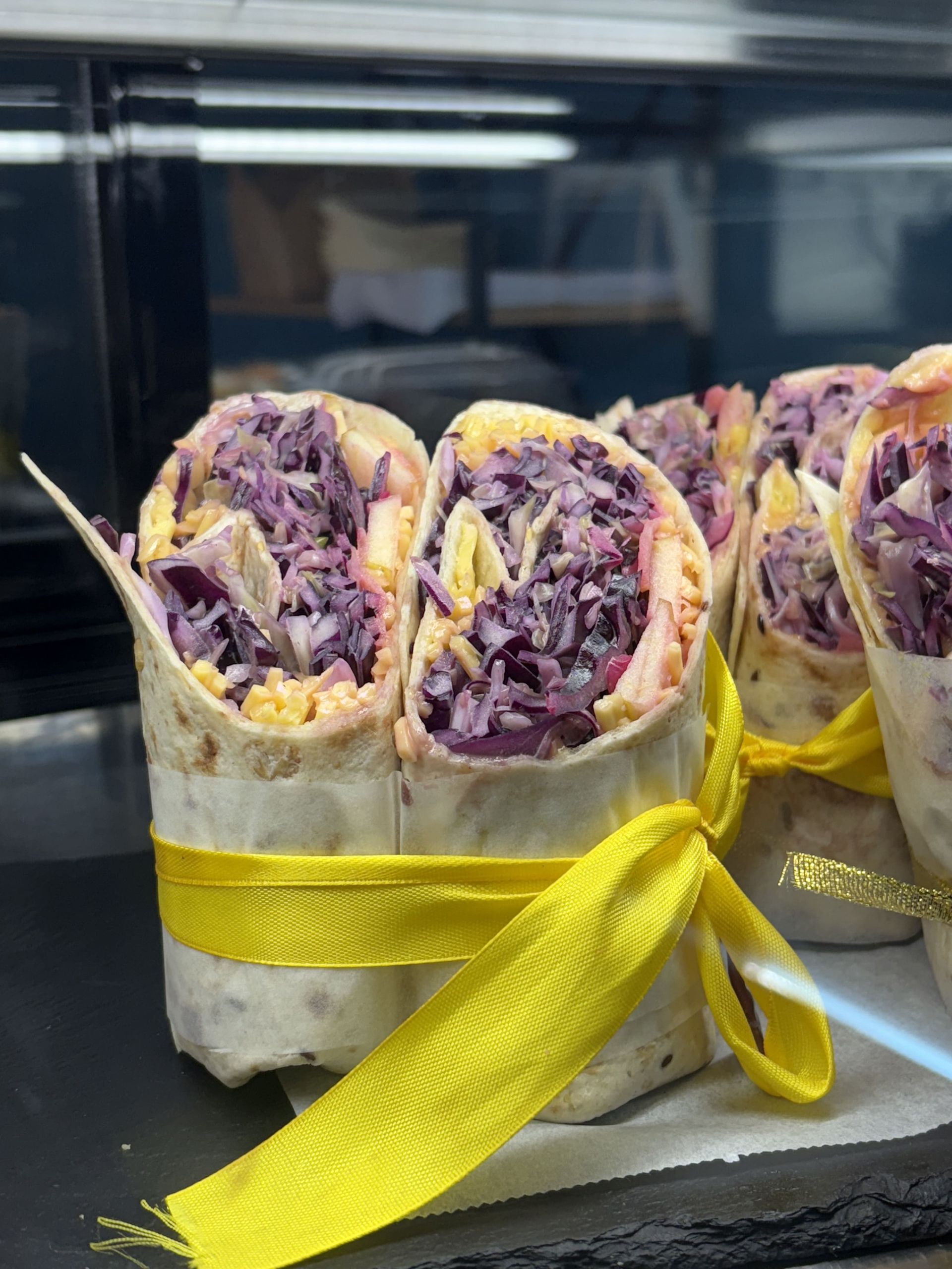 Wraps con relleno de col lombarda, atados con cinta amarilla.
