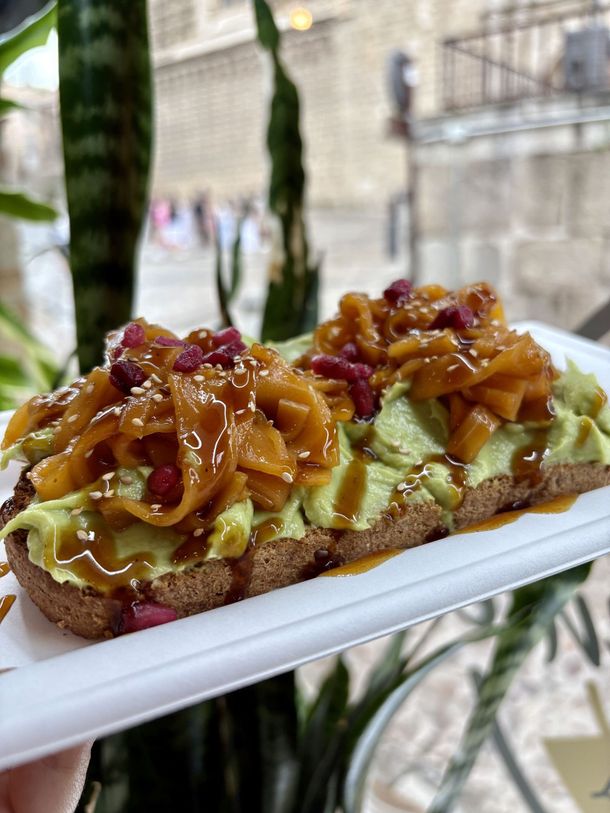 Barra de postres con crema de pistacho y frutos secos caramelizados en un plato blanco al aire libre.