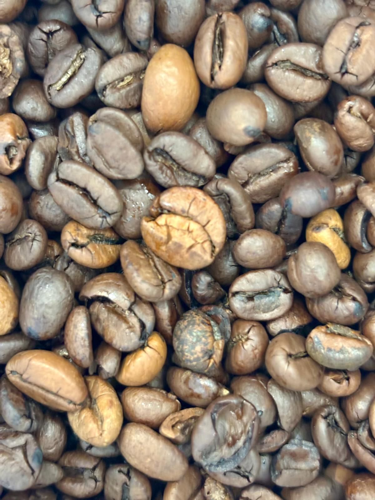 Granos de café de varios tonos de marrón, muy juntos. Algunos son de color más claro.