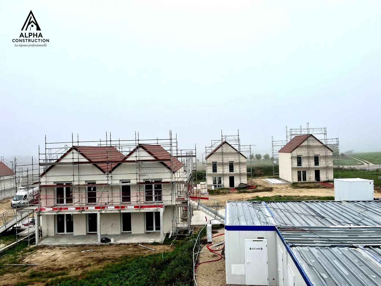 Maisons en construction dans un ciel nuageux et couvert. Des échafaudages entourent les structures.