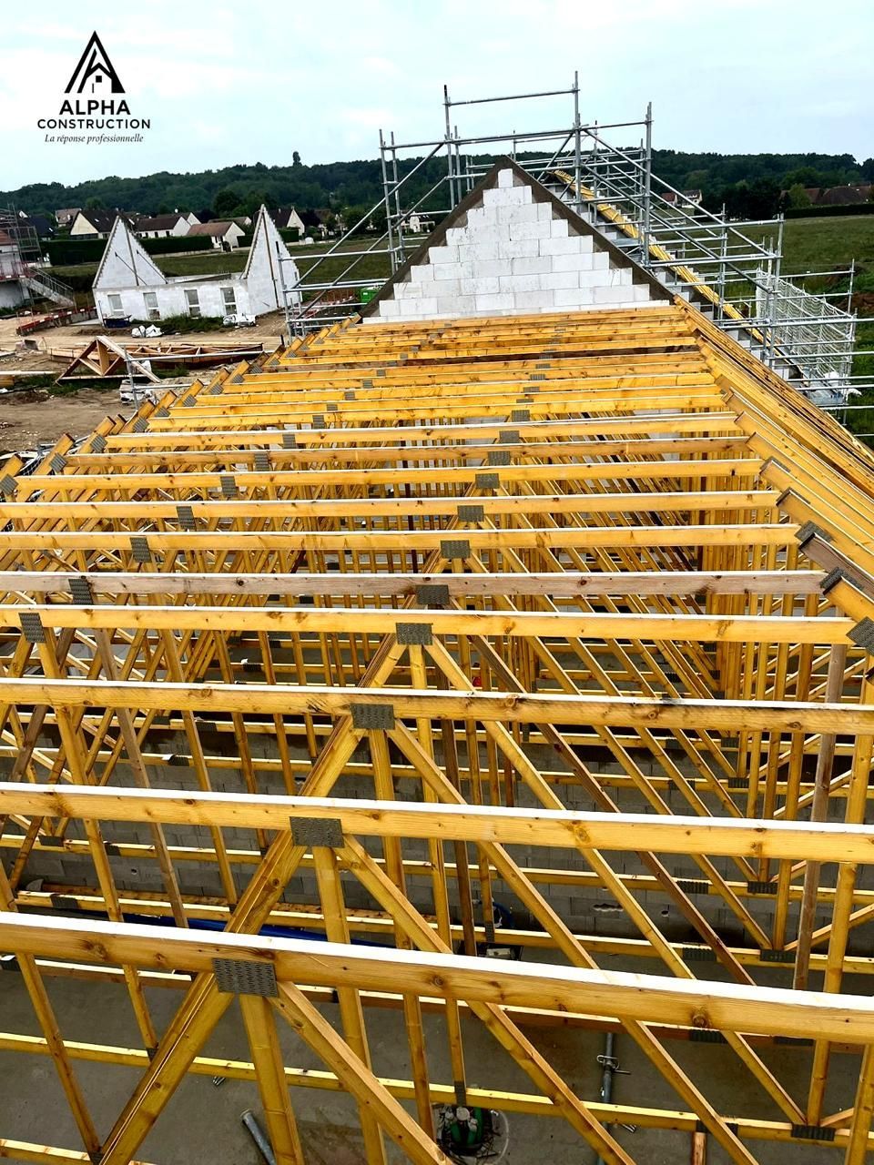 Chantier de construction. Fermes de toit en bois en cours de construction sur un bâtiment. Échafaudages et colline en arrière-plan.