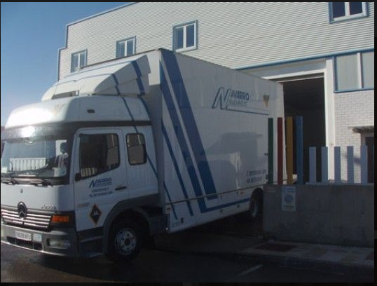 Un camión blanco con la palabra n en el costado está estacionado frente a un edificio.