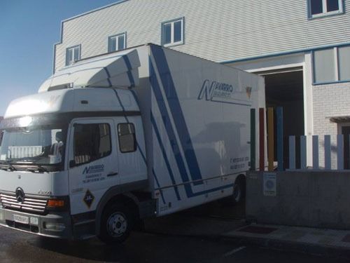 Un camión blanco y azul con la letra n en el costado está estacionado frente a un edificio.
