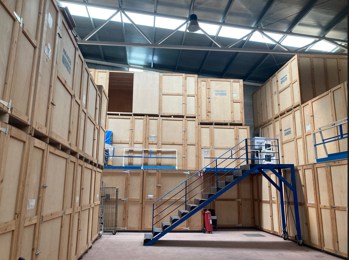 Un gran almacén lleno de cajas de madera y una escalera azul.