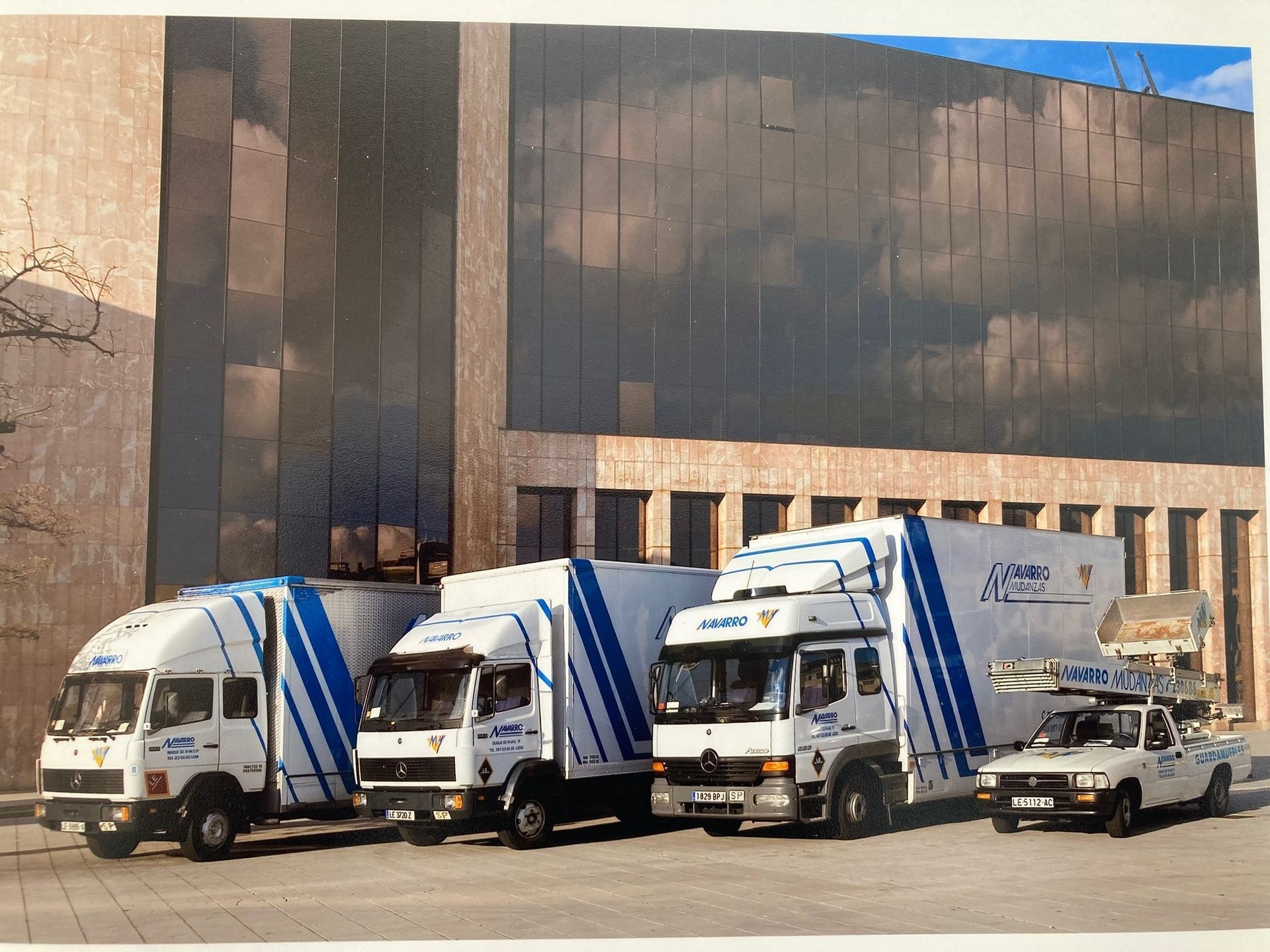 Un grupo de camiones están estacionados frente a un edificio.