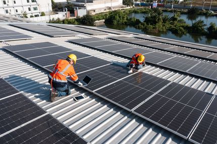 Ein Mann installiert Solarmodule auf dem Dach eines Gebäudes.