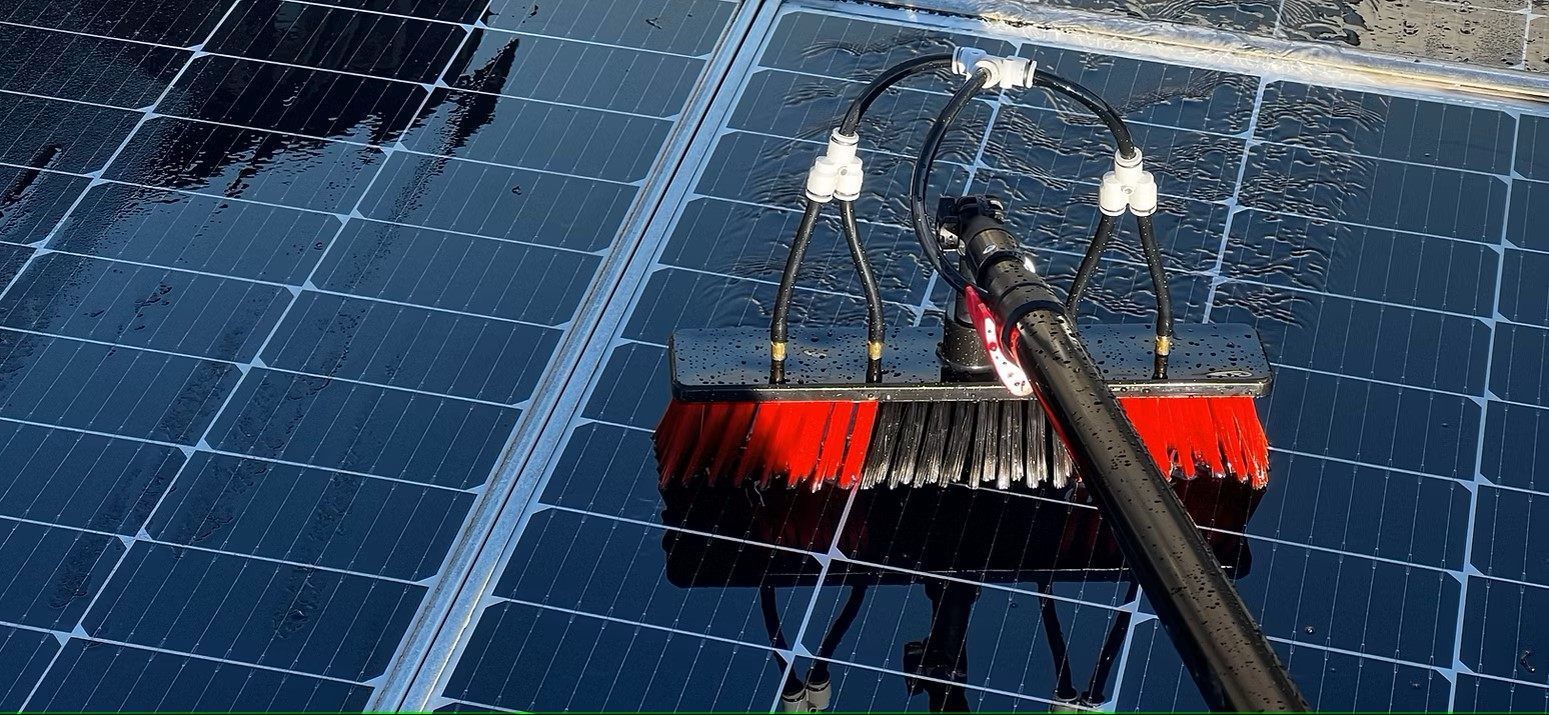 Eine Person reinigt ein Solarpanel mit einer Bürste.