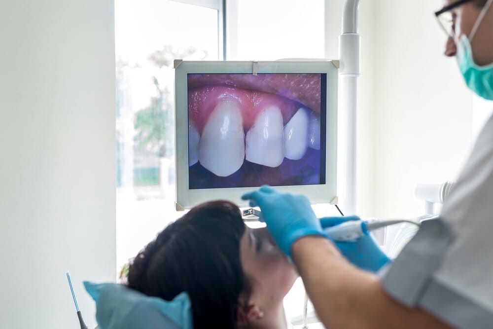 Un dentista está examinando los dientes de un paciente en un monitor.