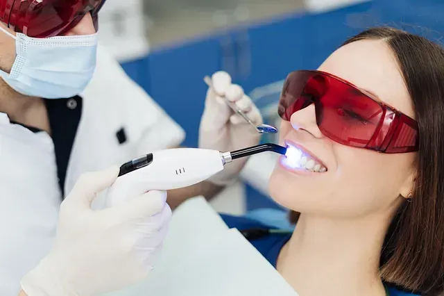 Una mujer se está blanqueando los dientes con un dentista.