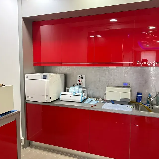 Una cocina con gabinetes rojos y electrodomésticos blancos.