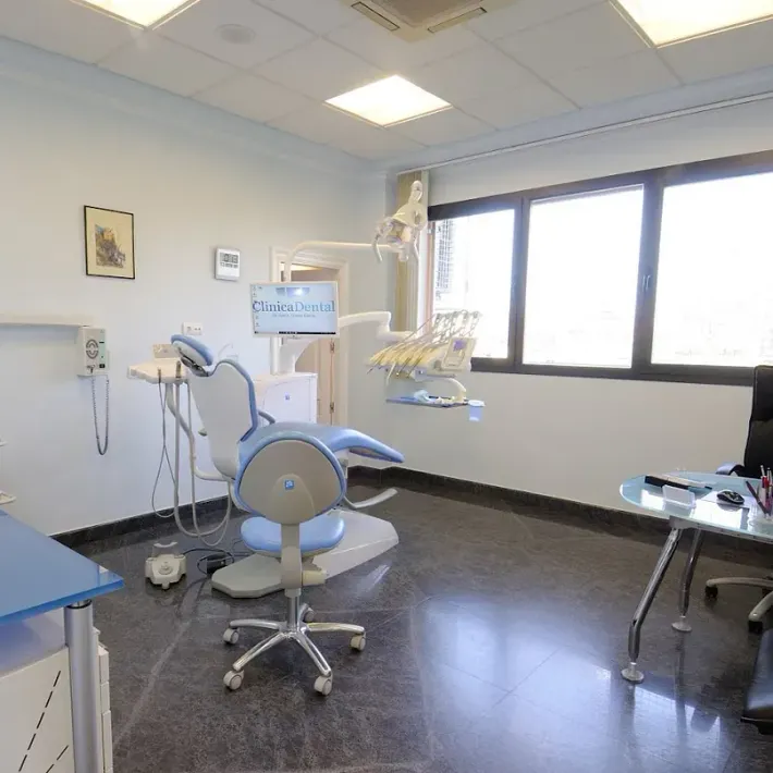 Un consultorio dental con un sillón dental y un escritorio.