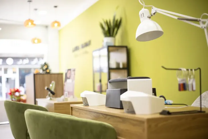 Sala de spa con varias máquinas de tratamientos faciales y camilla de masaje. Paredes beige.