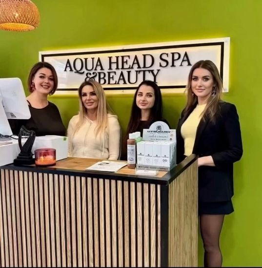 Mujer sonriendo, con la mano en la barbilla, frente a un cartel que dice