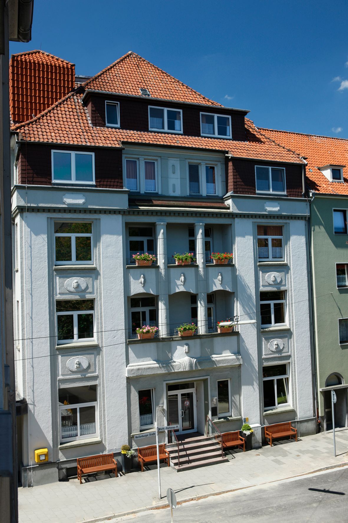 Ein großes weißes Gebäude mit einem roten Ziegeldach