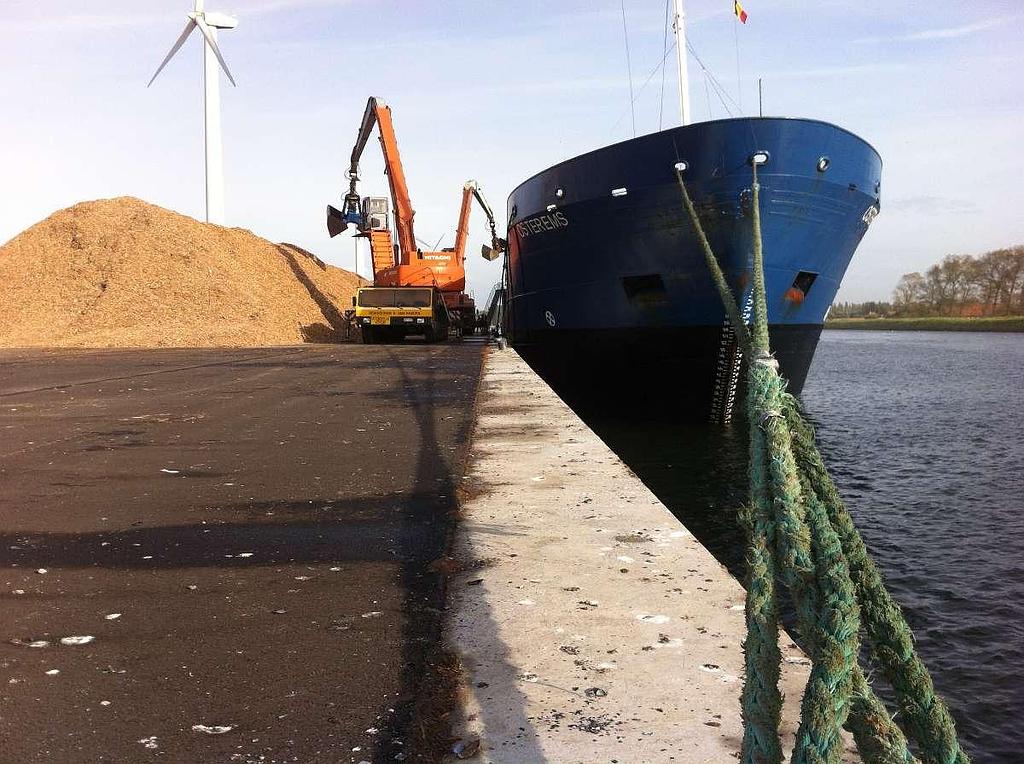 Pelleteuse procédant au chargement en bois recyclé d'un navire de transport de marchandise