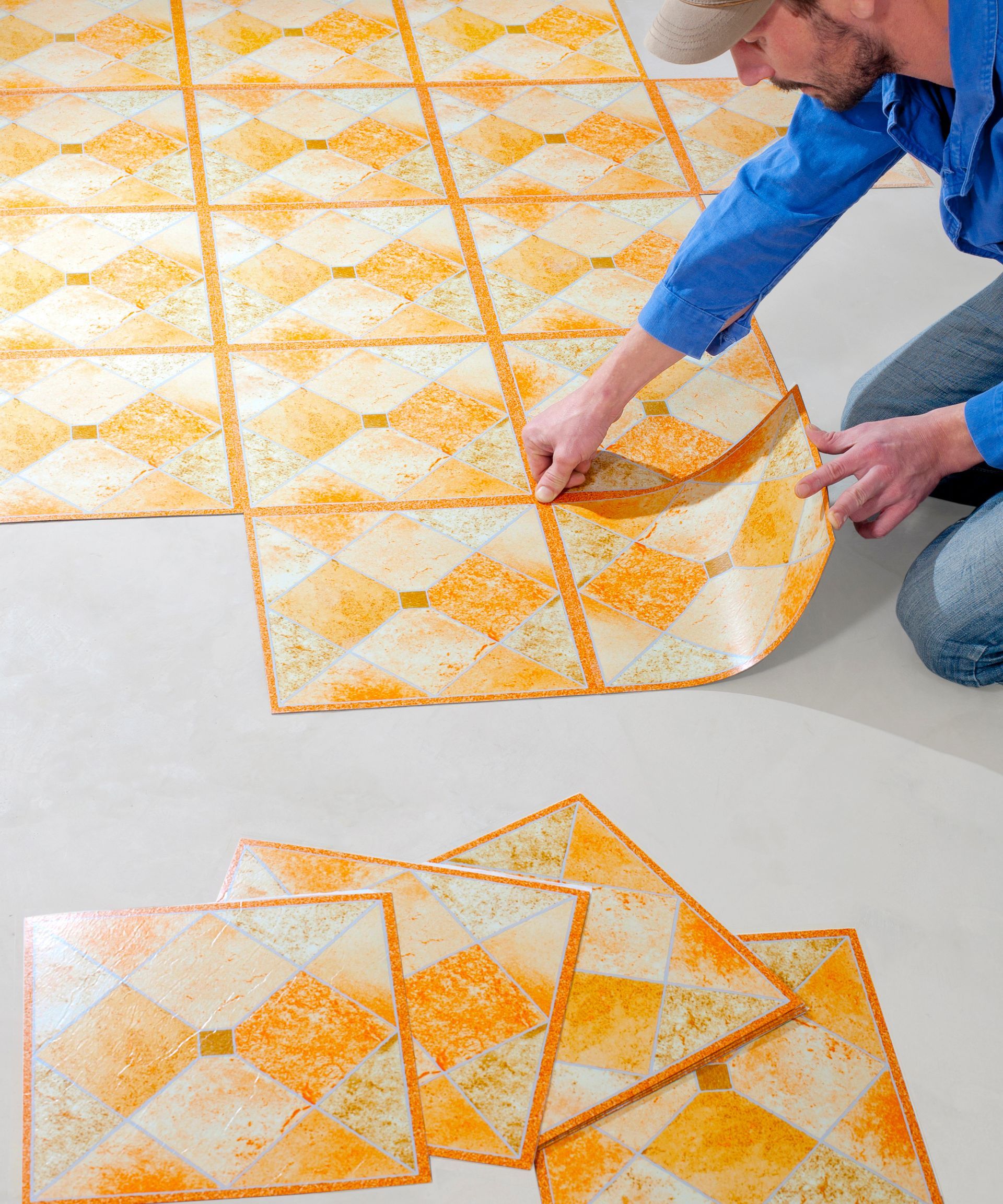 Homme installant un revêtement de sol à motifs autocollants, motif diamant orange et crème.